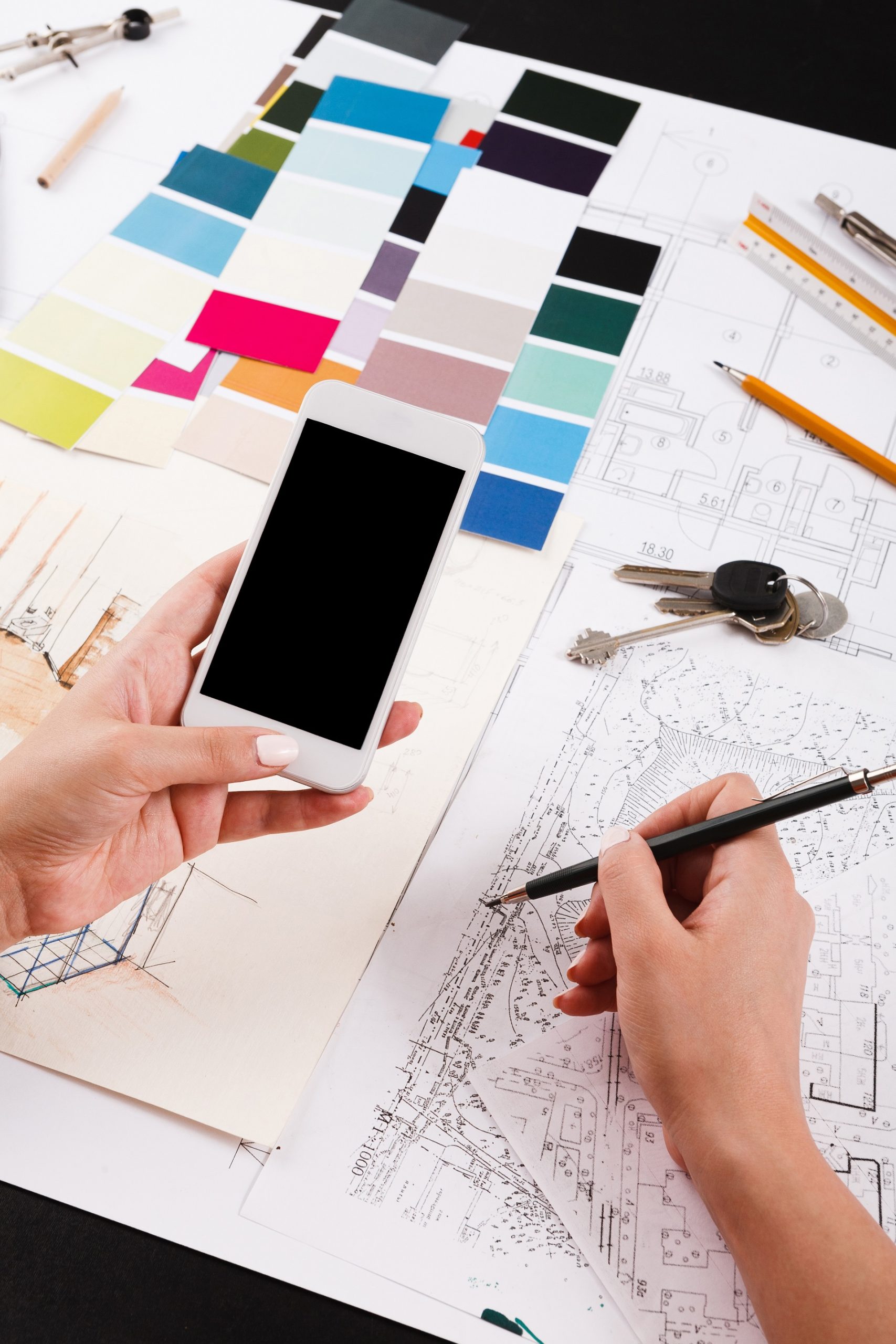 Architect drawing architectural project. Unrecognizable designer hands working with building blueprint, blank smartphone screen, mockup